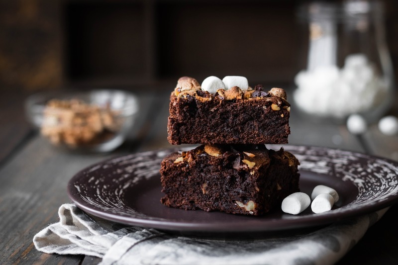 Sweet baked brownies sitting on a plate on top of each other with marshmallows