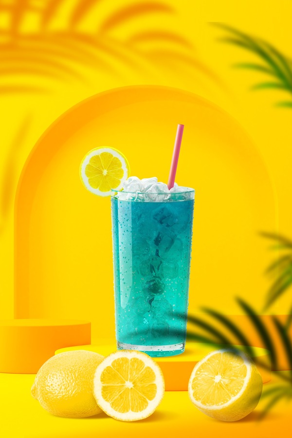 Blue sweet drink with ice and lemons on top with a straw on a yellow stand with lemons around