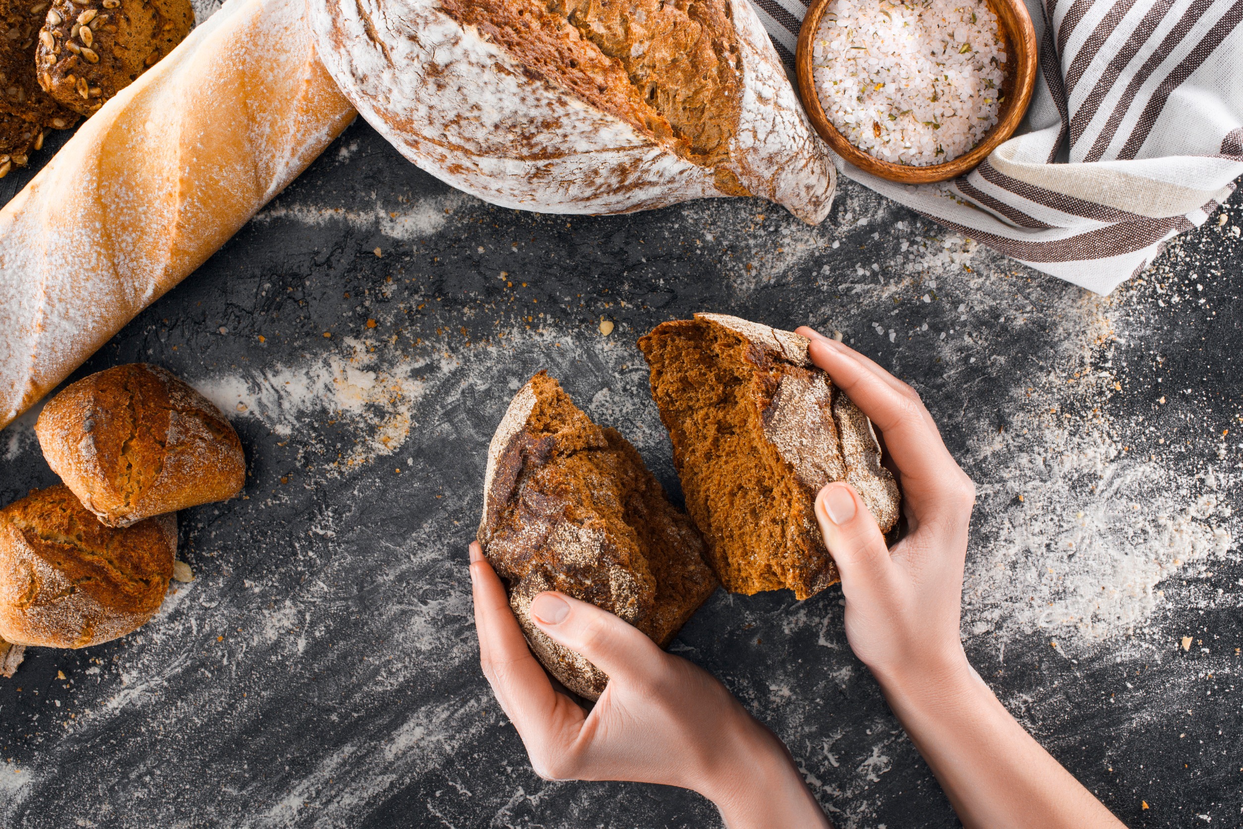 Hands holding a loaf of freshly baked bread