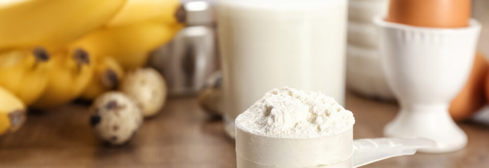 Pea protein powder in front of bananas, milk and a boiled egg
