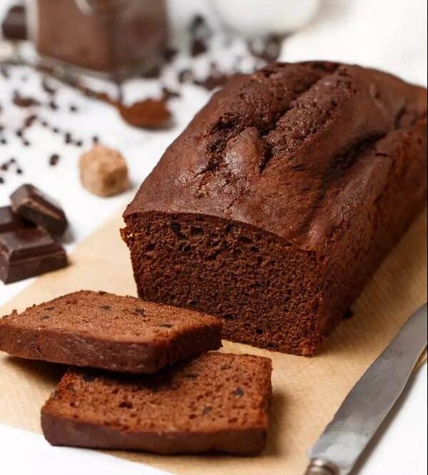 Some chocolate-baked bread with pieces of chocolate and a knife nearby