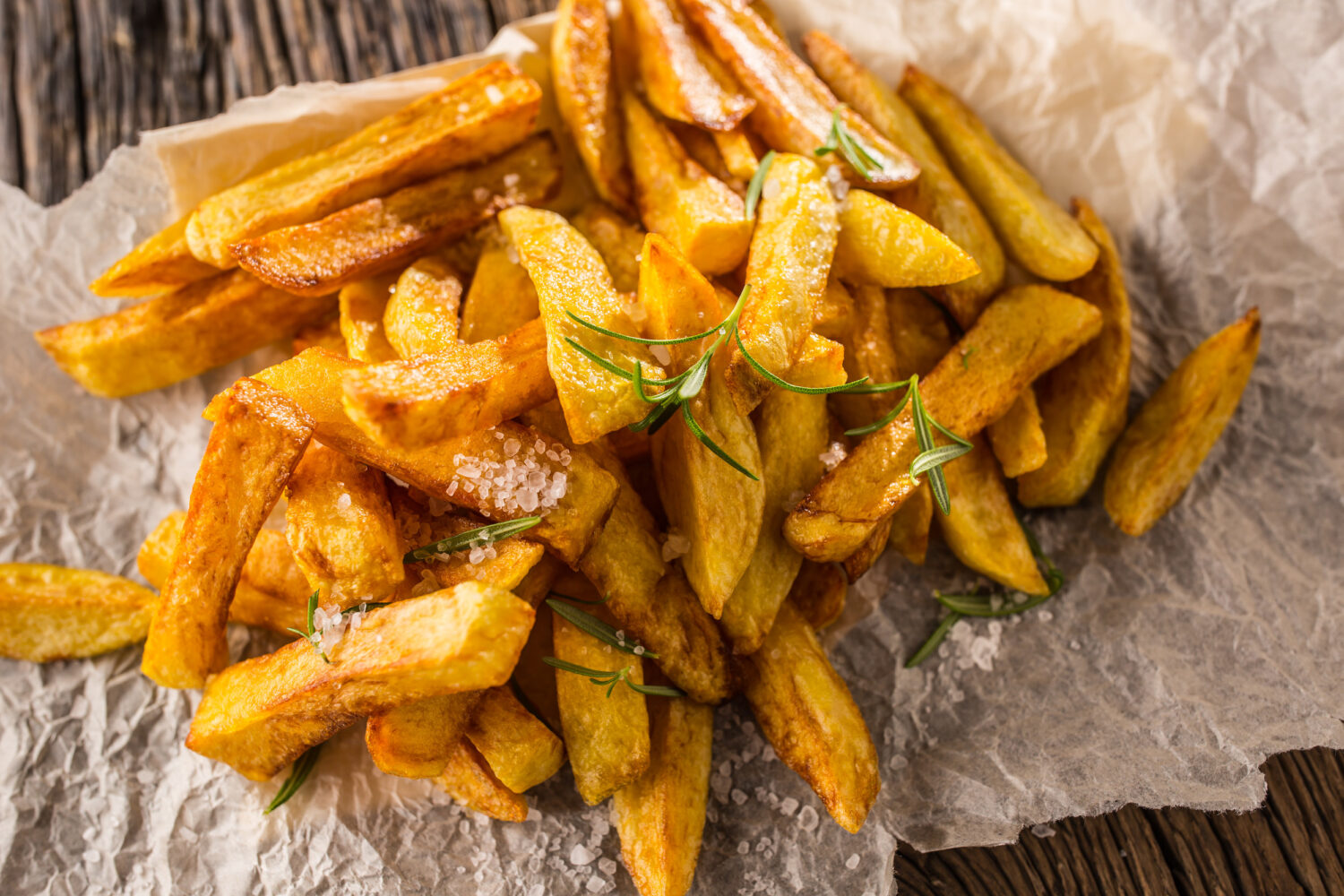 Potato Fries-oils Close-up of potato fries seasoned with salt and garnished with fresh rosemary sprigs.