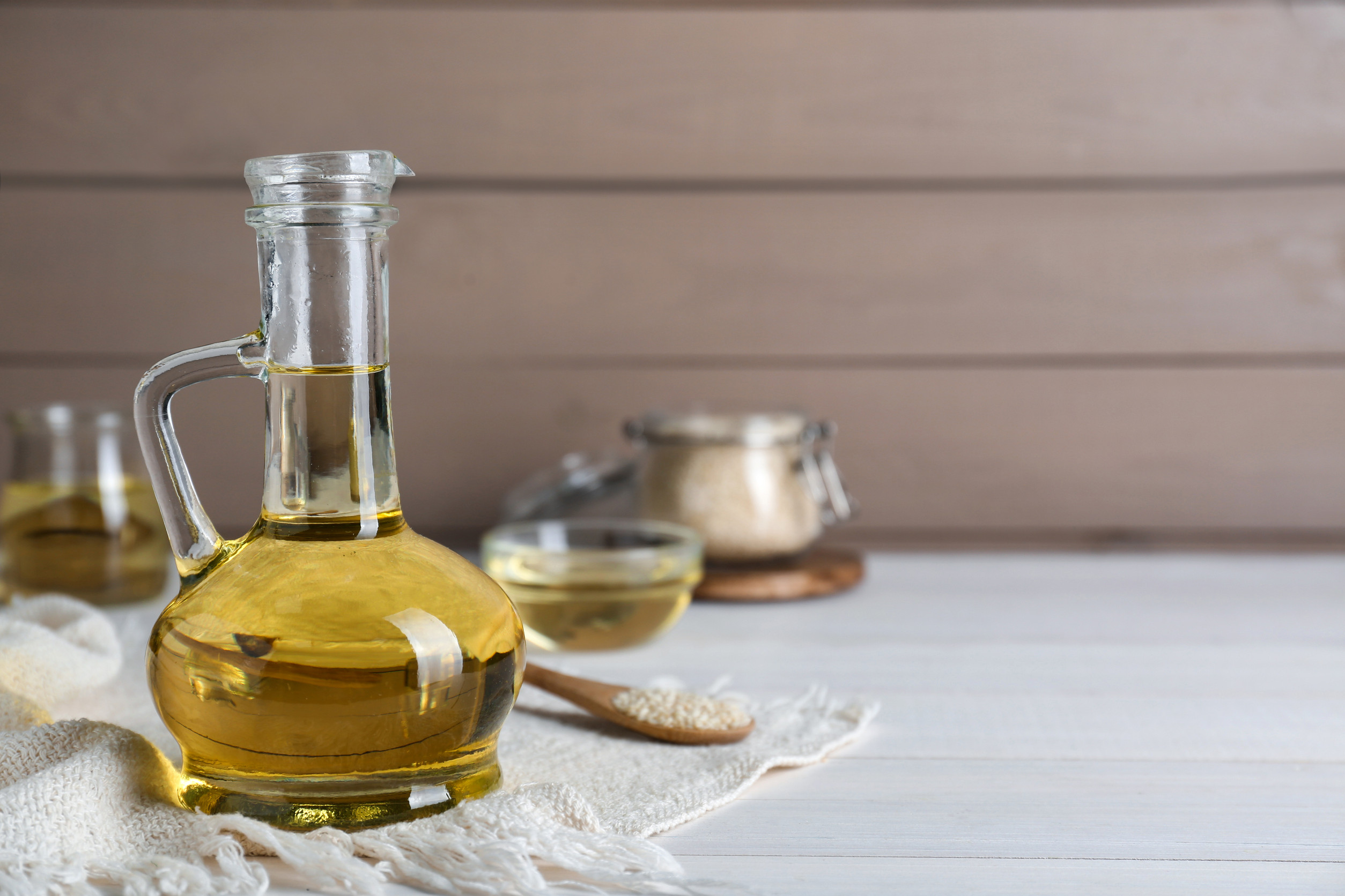 oils-gillco A jug filled with organic canola oil placed on a white wooden table.