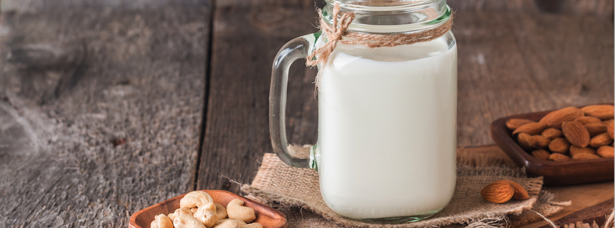 Nut milk in a jar and nuts on a table