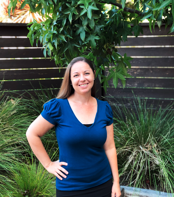 Employee smiling in front of tree