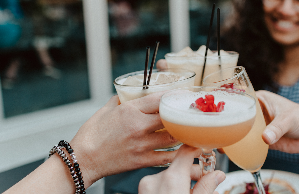 young people drinking cocktails cheers