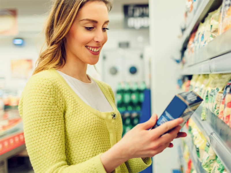 woman reading nutrition label at grocery store