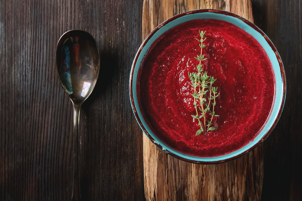 bowl of soup next to spoon wood background