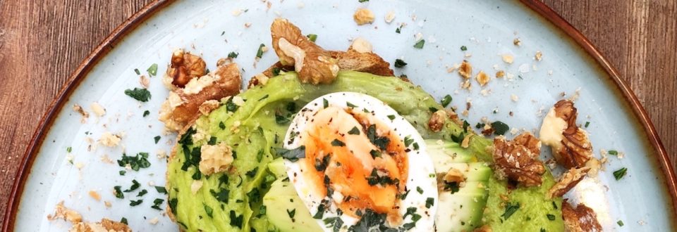 A delicious avocado toast with an egg and some walnuts