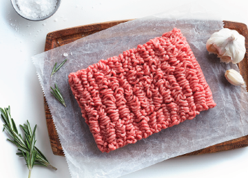 ground beef on a cutting board with fresh rosemary and garlic