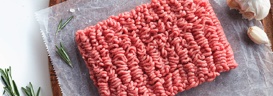 ground beef on a cutting board with fresh rosemary and garlic