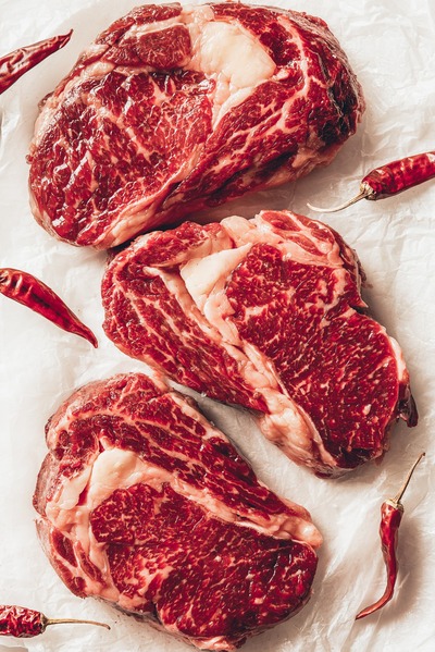 textured meat on a white background with red peppers