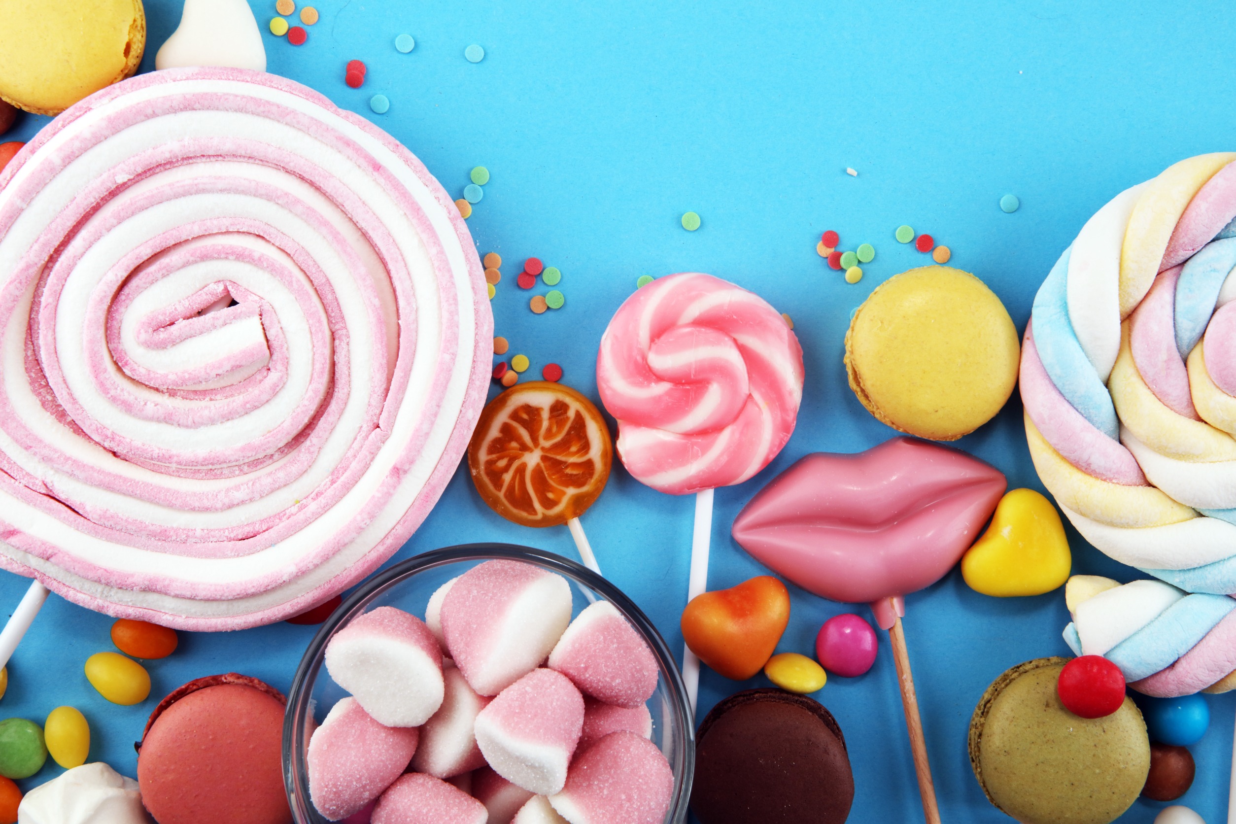 healthy candy and confectionery ingredients arranged in a semicircle against a bright blue background