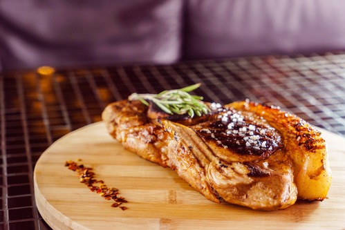 glazed meat on a wooden board with rosemary on top