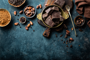 cocoa beans and cocoa powder and chocolate on a dark blue tabletop
