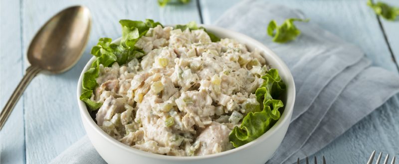 bowl of chicken salad with a spoon resting next to the bowl