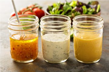 three mason jars filled with different salad dressings