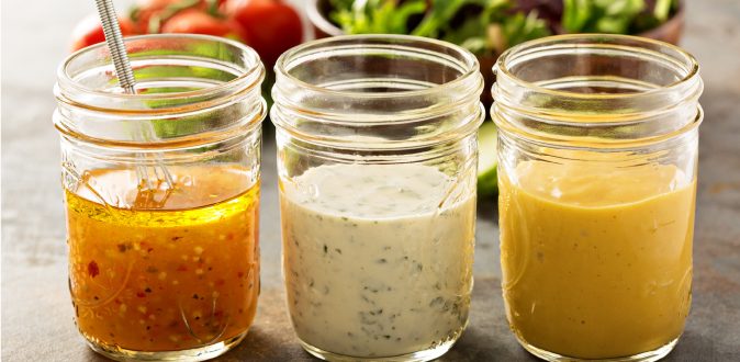 three mason jars filled with different salad dressings