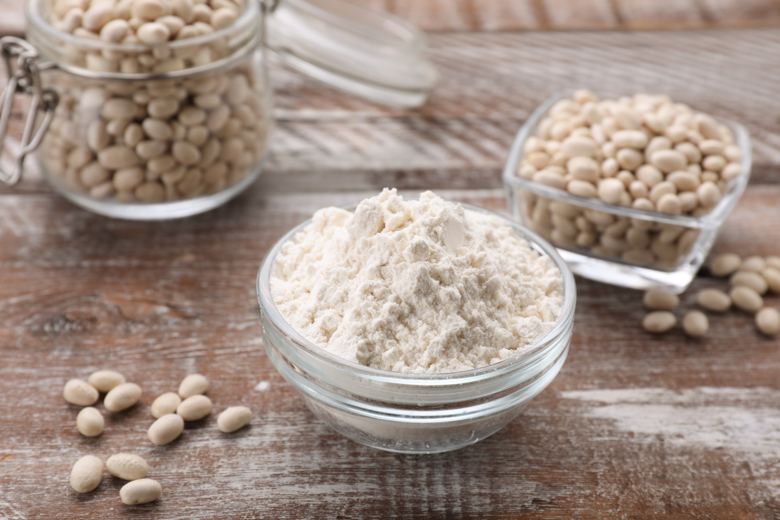 Soy protein isolate next to bowls of soybeans