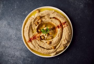 A bowl of hummus with a garnish on top