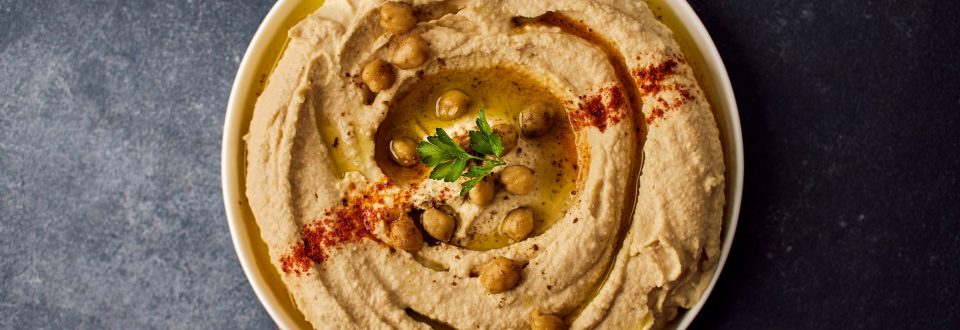 A bowl of hummus with a garnish on top