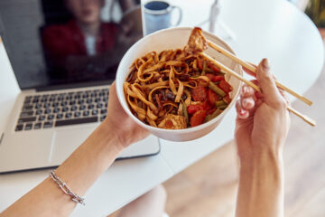 Ready-to-eat Asian noodle dish with laptop and office in the background