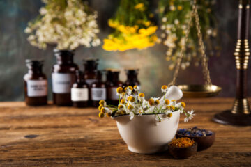 Chamomile flowers in a mortar with organic botanical extracts in the background