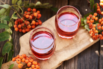 Two glasses of fresh hawthorn extract, garnished with leaves.