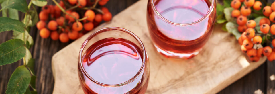 Two glasses of fresh hawthorn extract, garnished with leaves.