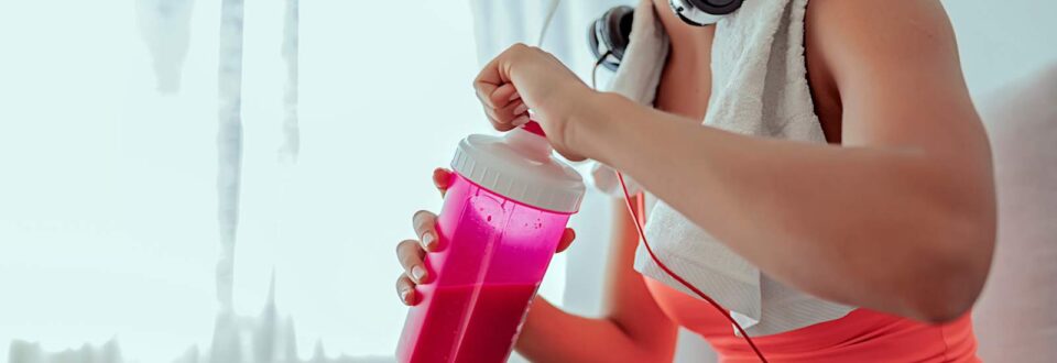 woman smiling and drinking a protein shake after a workout