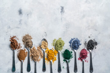 Spoons on a table full of different powdered natural color food dyes