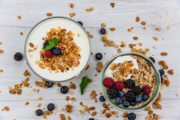 protein-fortified yogurt with granola and fresh berries on a white wooden table