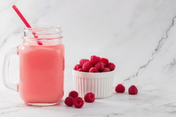 Prebiotic raspberry drink in a glass jar with fresh raspberries nearby